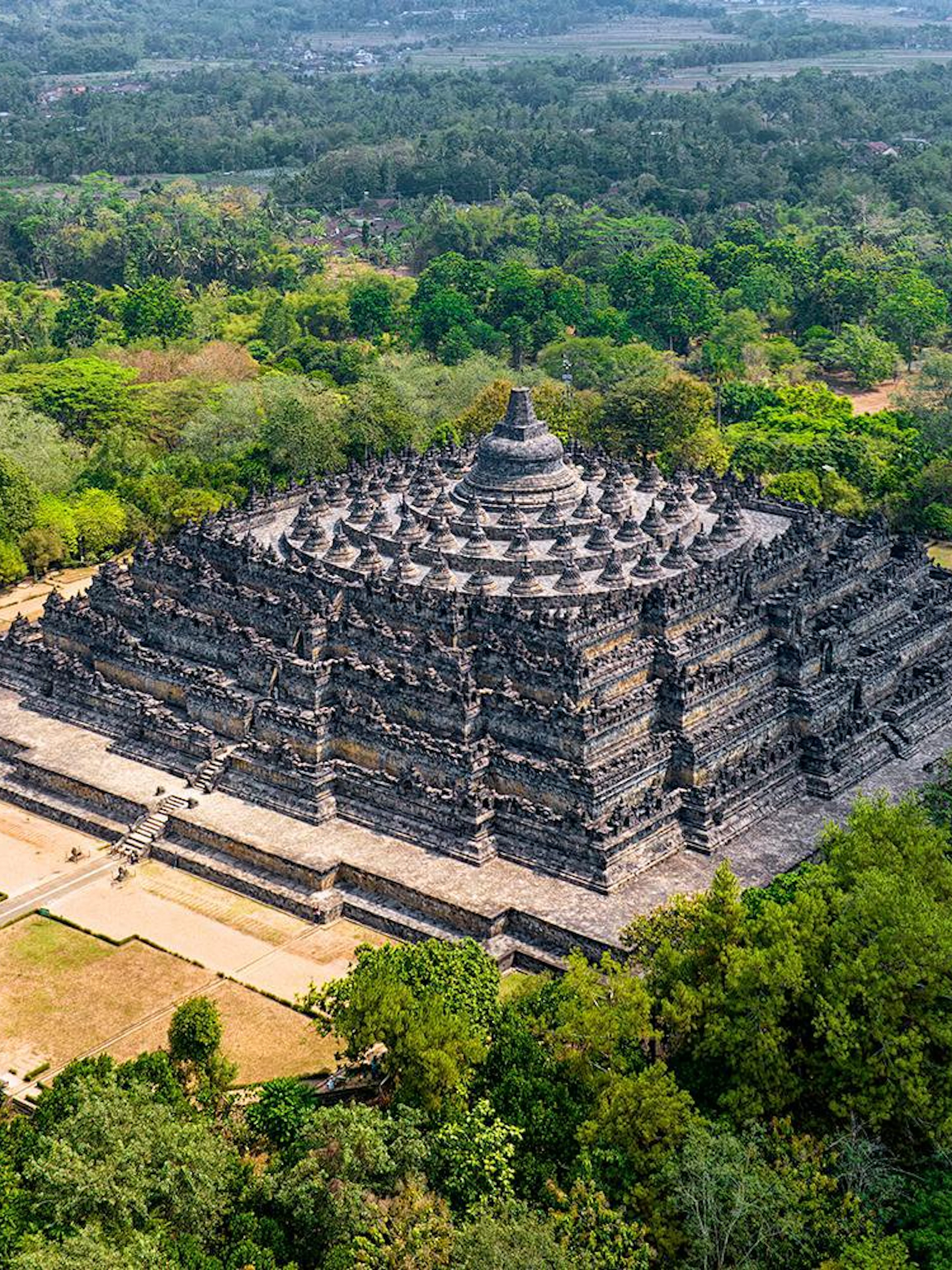 Aerial view of Borobudur Temple surrounded by lush greenery in Yogyakarta, Java, Indonesia.