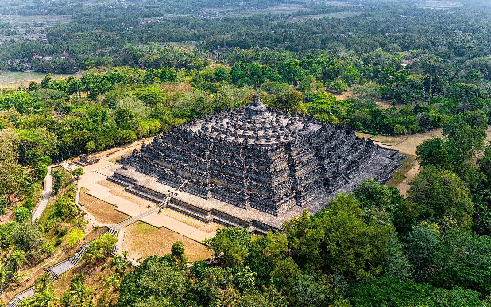 Aerial view of Borobudur Temple surrounded by lush greenery in Yogyakarta, Java, Indonesia.