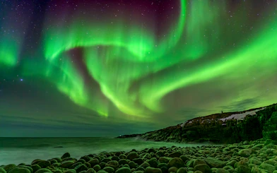 Northern Lights over rocky coastline in Iceland.