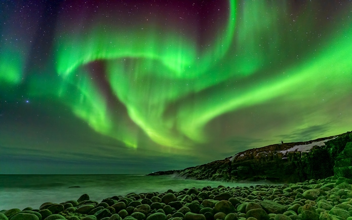 Northern Lights over rocky coastline in Iceland.