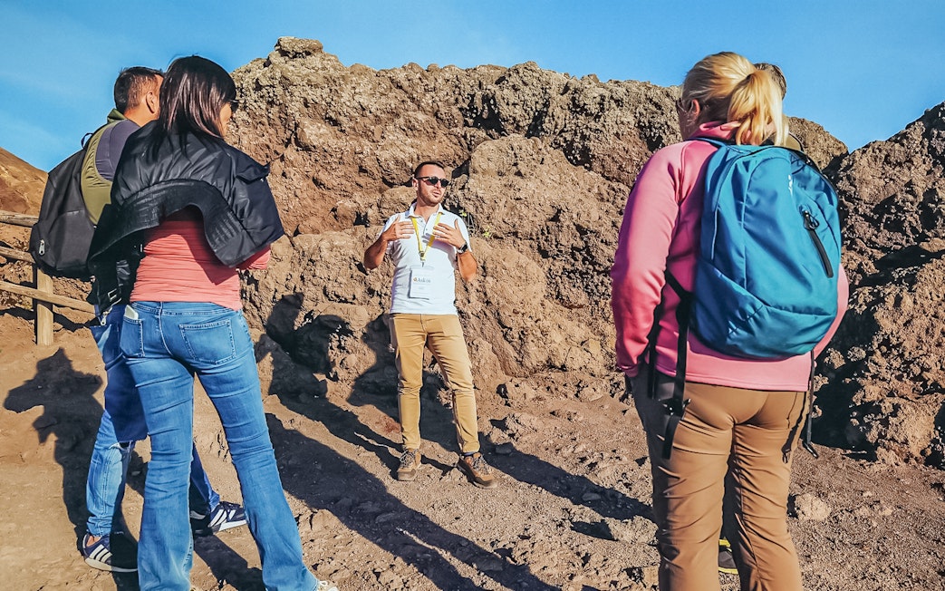 Tourists listening to a volcanologist guide during a hike on Mount Vesuvius.