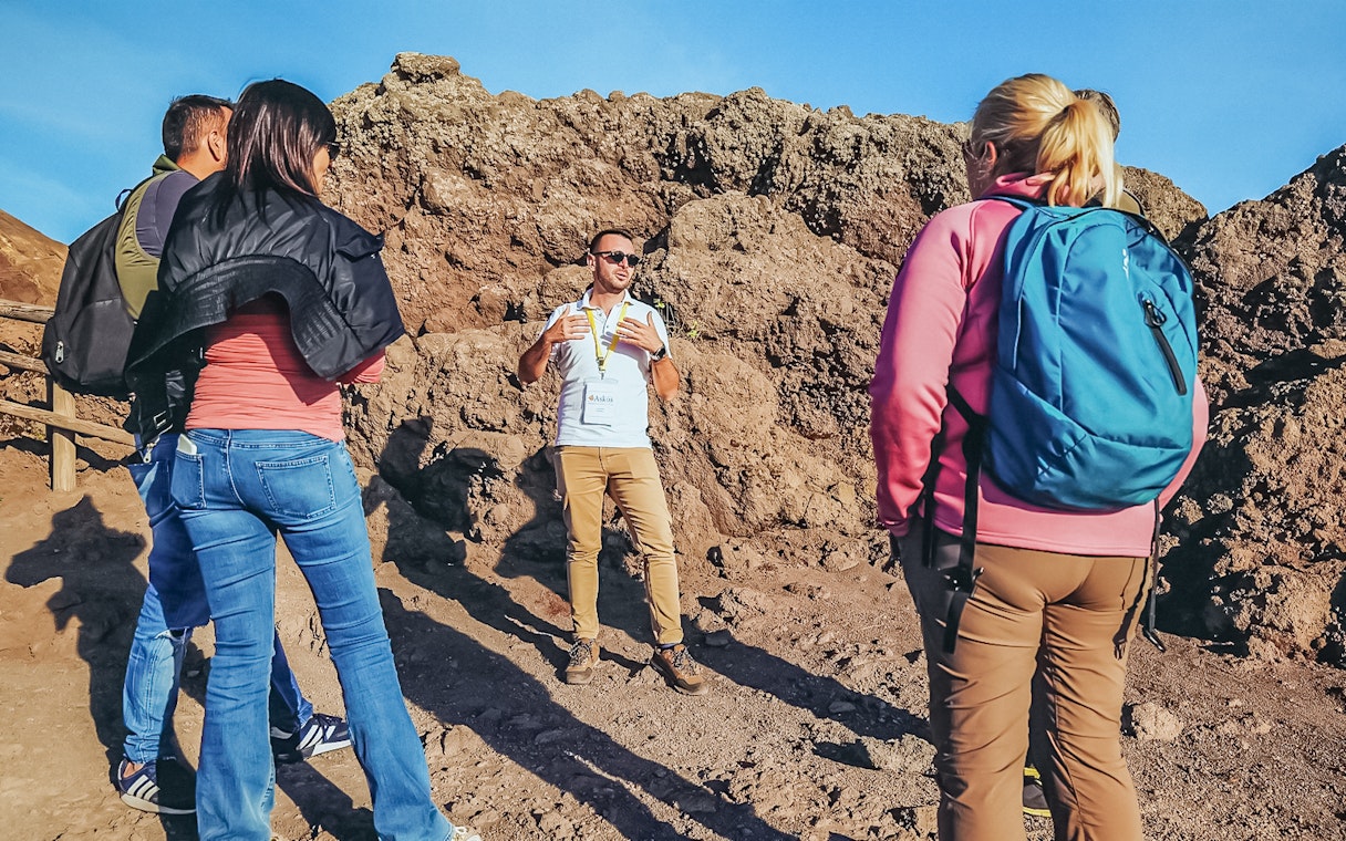 Tourists listening to a volcanologist guide during a hike on Mount Vesuvius.