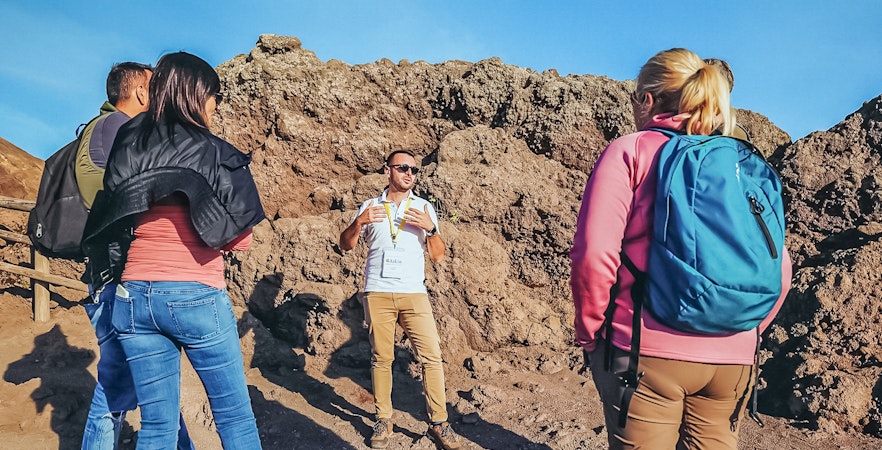 Tourists listening to a volcanologist guide during a hike on Mount Vesuvius.