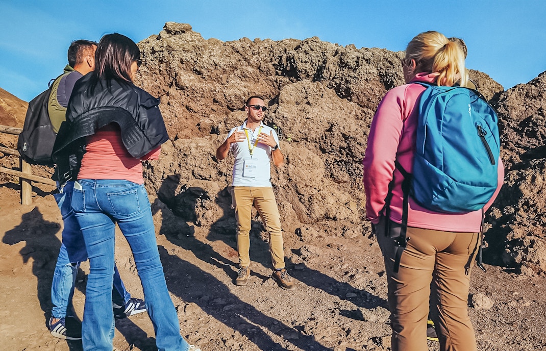 Tourists listening to a volcanologist guide during a hike on Mount Vesuvius.