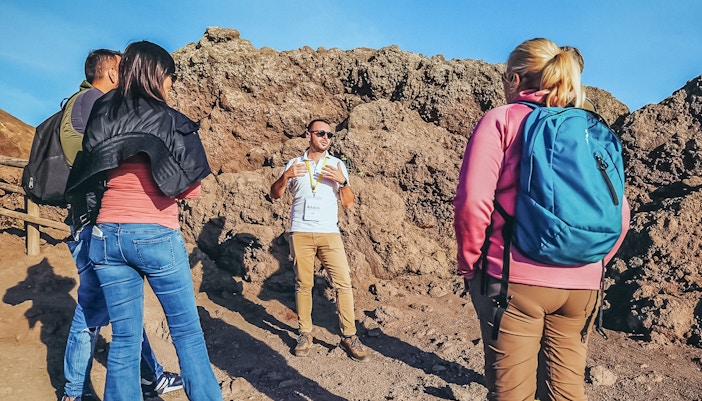 Tourists listening to a volcanologist guide during a hike on Mount Vesuvius.