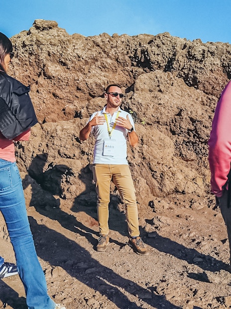 Tourists listening to a volcanologist guide during a hike on Mount Vesuvius.