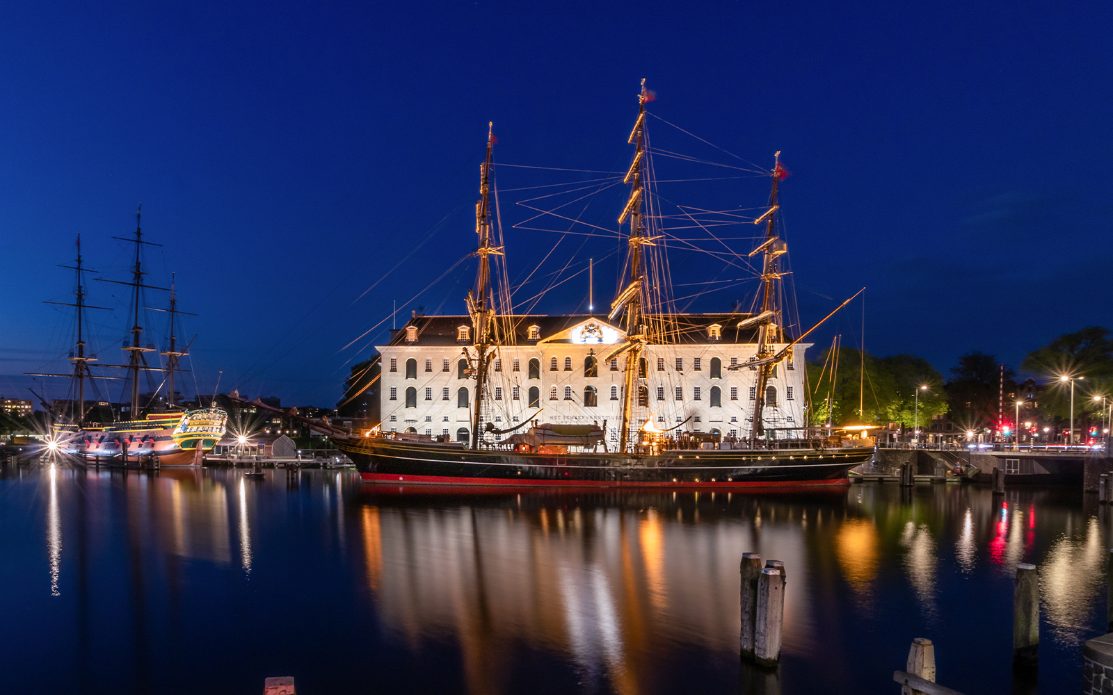Maritime Museum Amsterdam with historic ship replica in harbor.