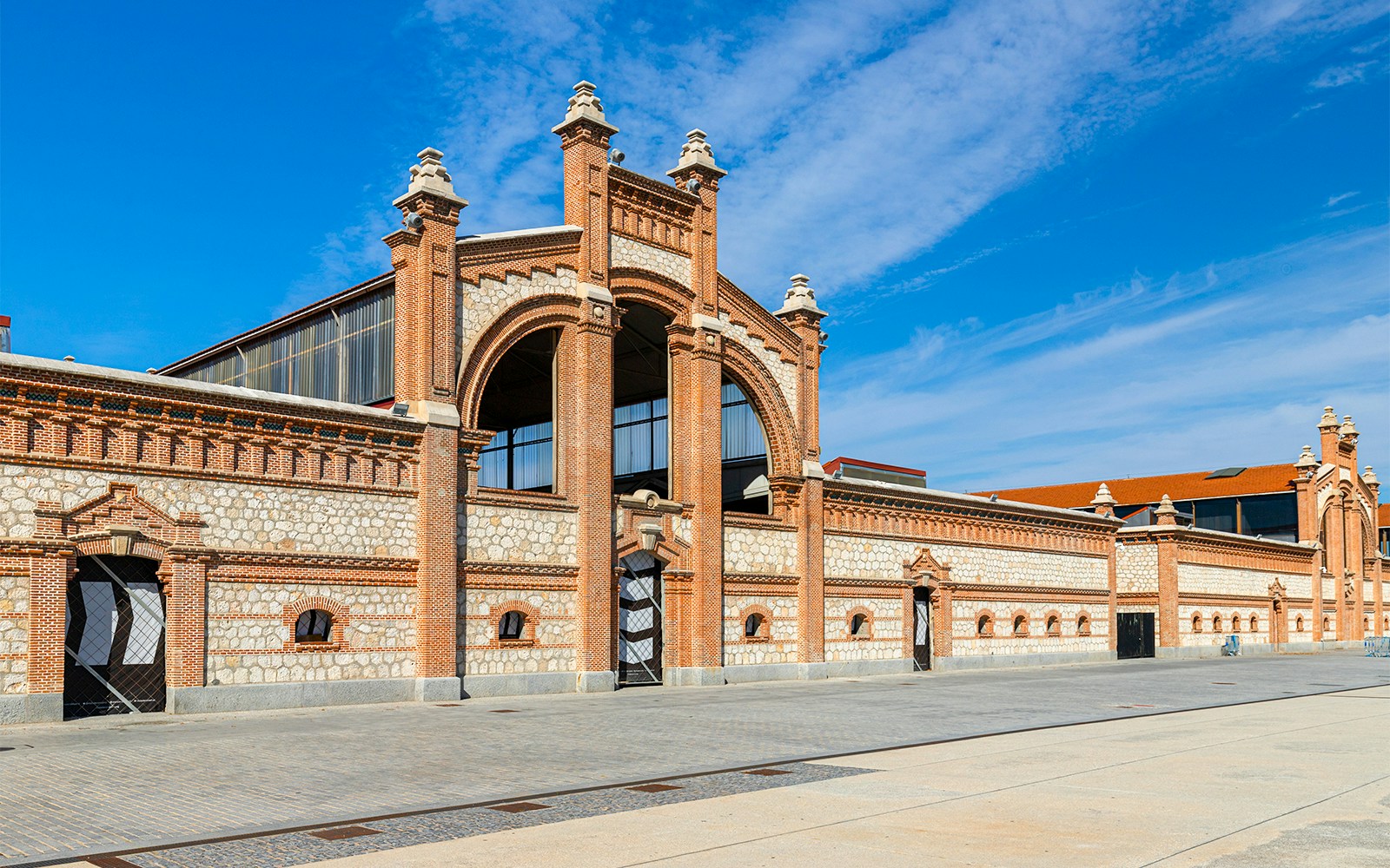Historic Matadero Madrid building with brick and stone facade under blue sky.