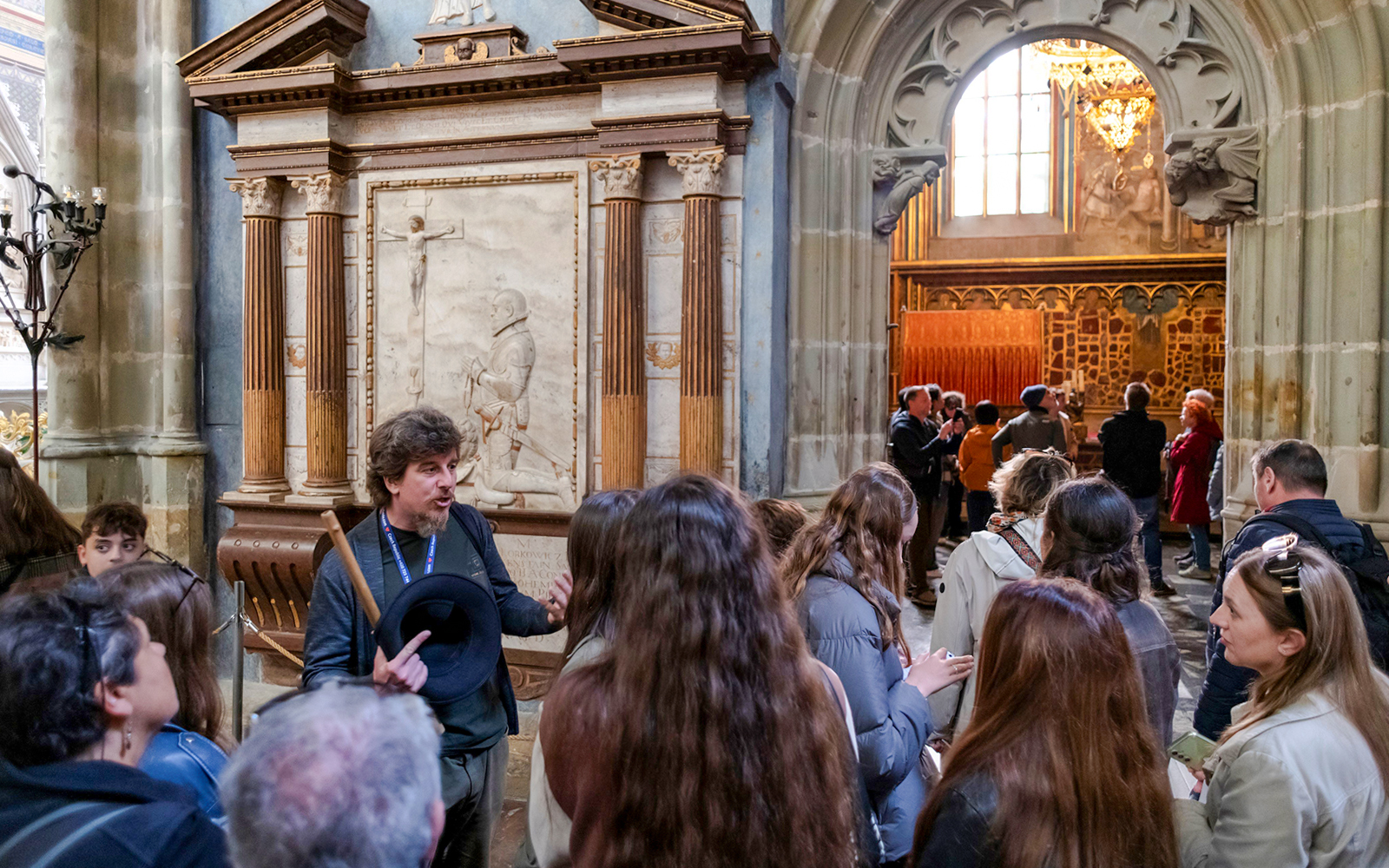 Guide explaining historical details to tourists inside Prague Castle.