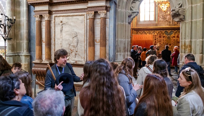 Guide explaining historical details to tourists inside Prague Castle.