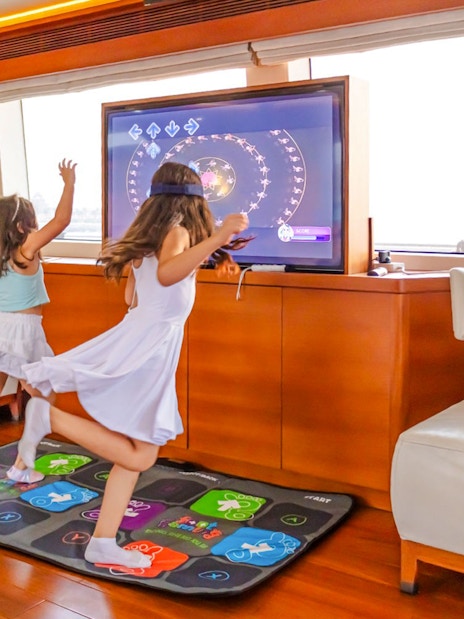 Kids engaging with interactive TV games on a yacht cruise in Dubai.