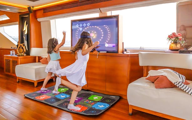 Kids engaging with interactive TV games on a yacht cruise in Dubai.
