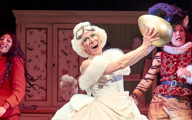 Performer in Mother Goose play holding a golden egg on stage.