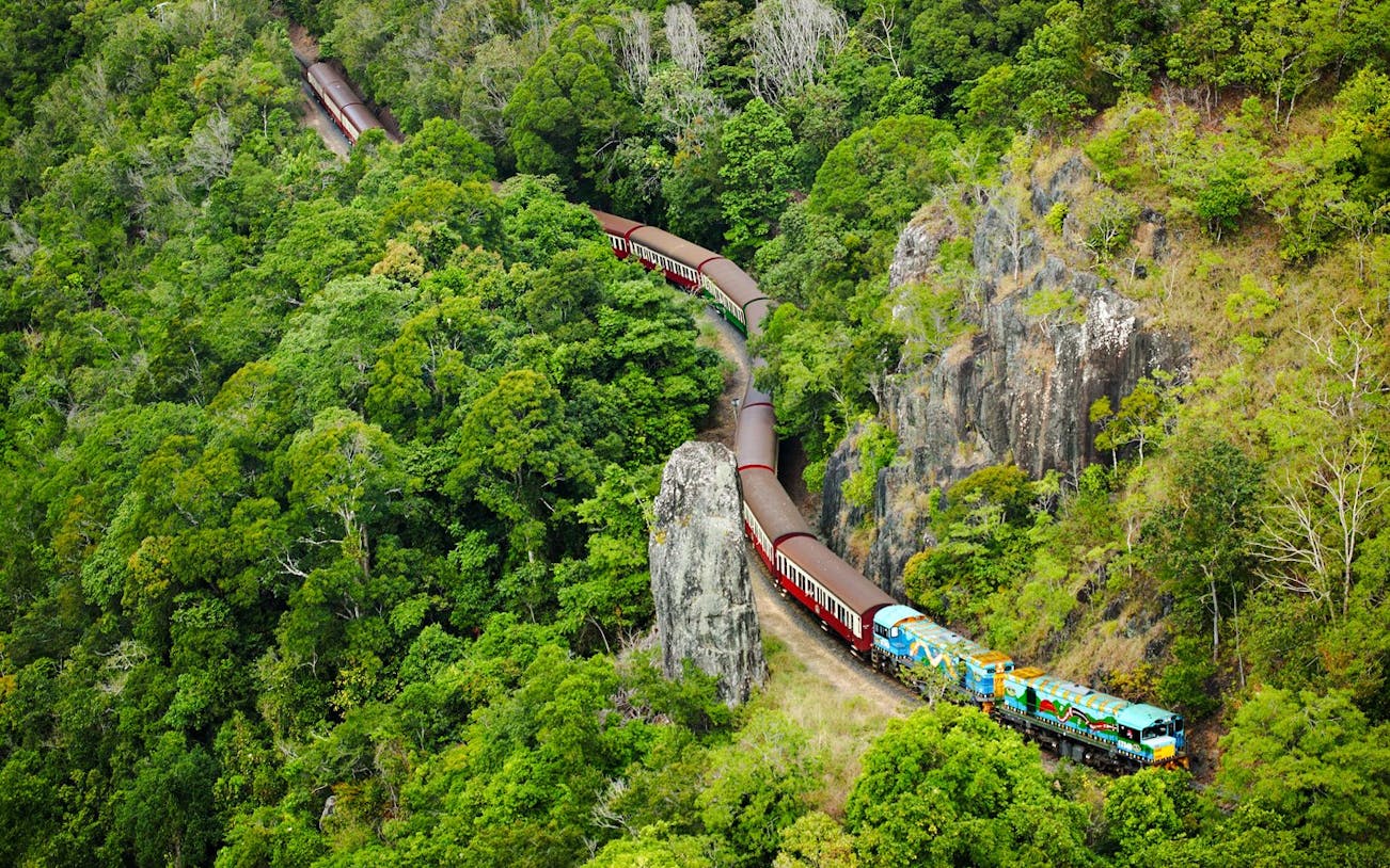 Scenic train winding through lush rainforest near Kuranda, Australia.