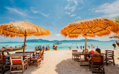 Speedboats anchored near Koh Samui's Pig Island beach with tourists and straw umbrellas.