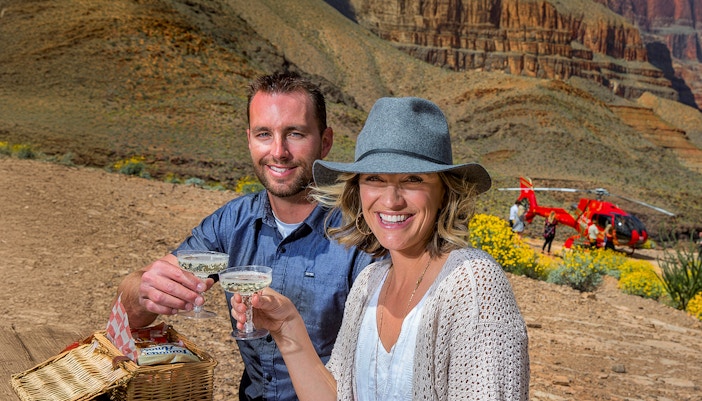Helicopter landing on Grand Canyon floor during sunset, Las Vegas, with champagne picnic setup.