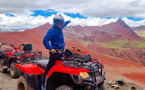 ATV rider pointing at Rainbow Mountain and Red Valley, Cusco.