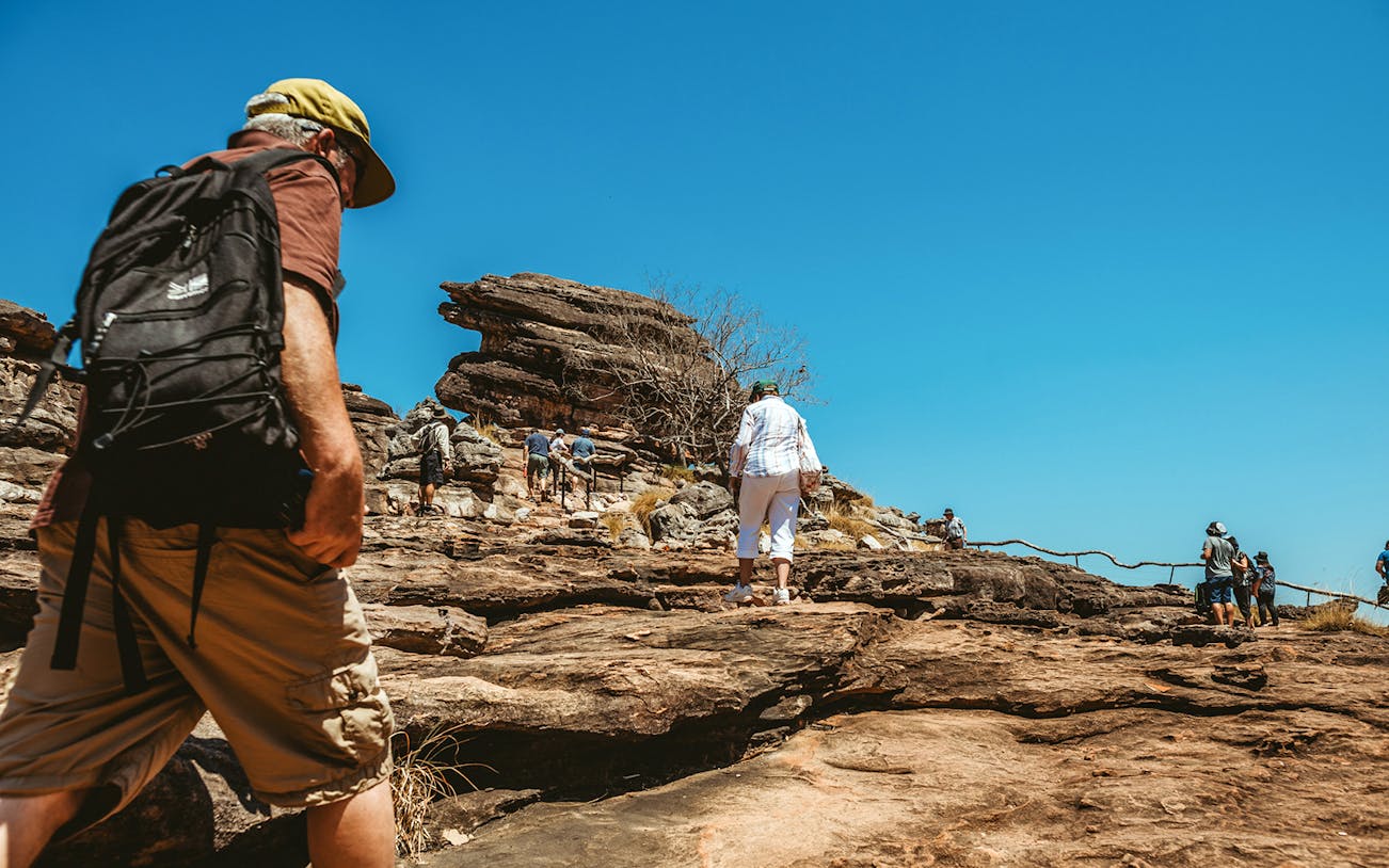 Visitors hiking rocky terrain on Kakadu Public Day Tour, Northern Territory, Australia.