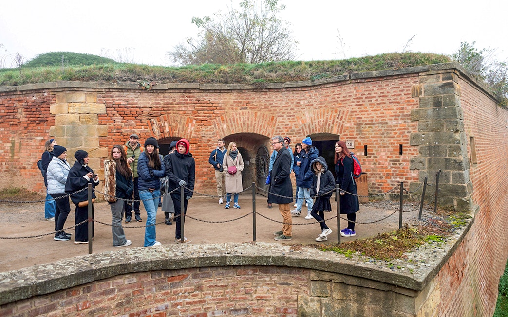 Tour group listening to guide at Terezin Concentration Camp historic site.