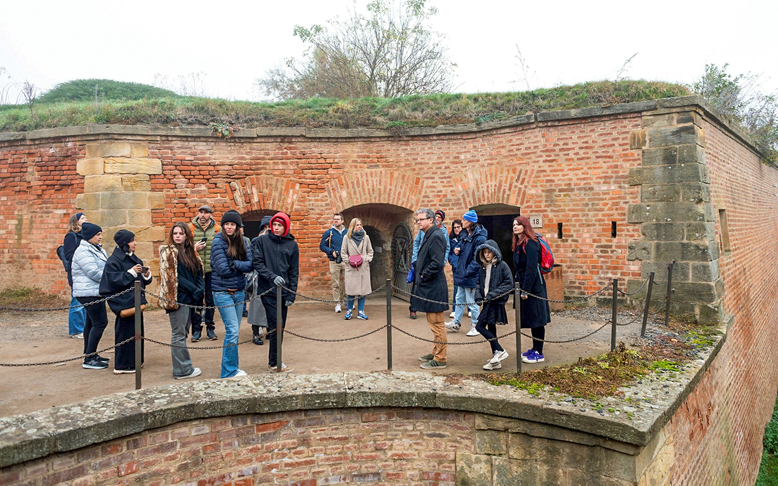 Tour group listening to guide at Terezin Concentration Camp historic site.