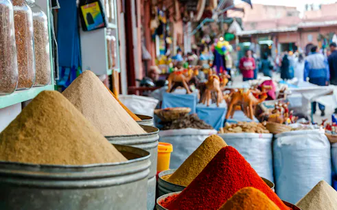 Spice market stalls with colorful spices and crafts in Marrakesh.
