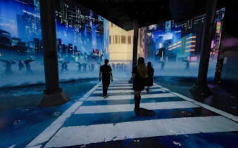 Visitors walking through immersive digital cityscape at ARTECHOUSE DC exhibit.