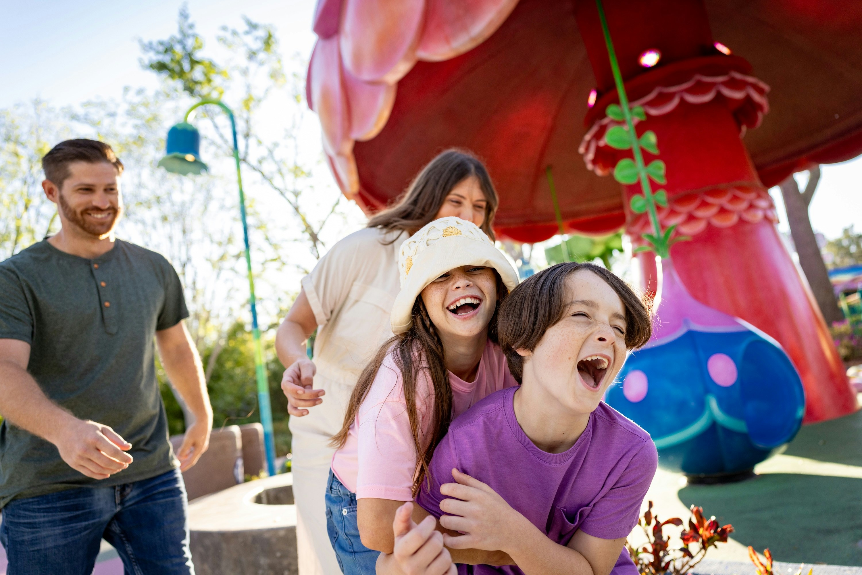 Family enjoying playful moments at Universal Kids Resort with colorful mushroom structure.