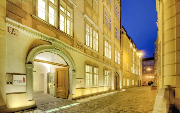 Exterior of Mozarthaus Vienna at night with illuminated windows.
