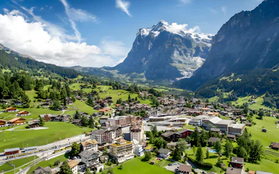 Grindelwald village in a lush valley with mountains in the background, Switzerland.