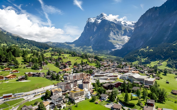 Grindelwald village in a lush valley with mountains in the background, Switzerland.
