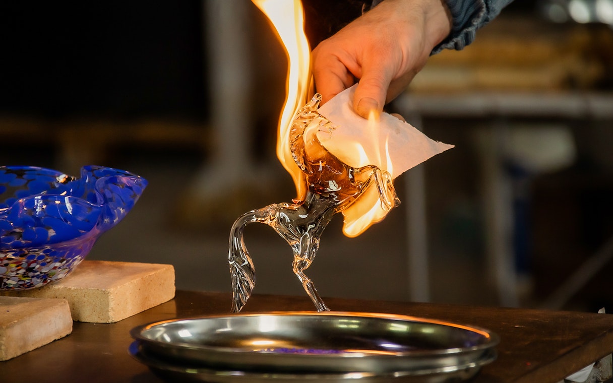 Glassblowing demonstration in Murano, Venice with a flaming glass horse sculpture.