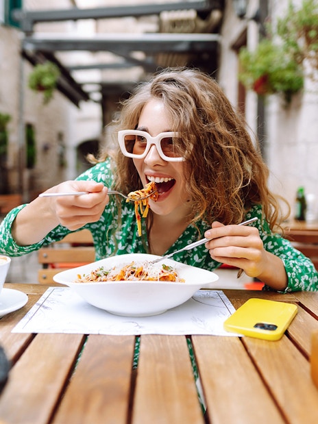 Woman enjoying pasta at an outdoor cafe in Rome.