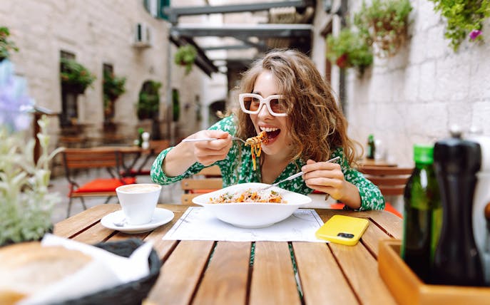 Woman enjoying pasta at an outdoor cafe in Rome.