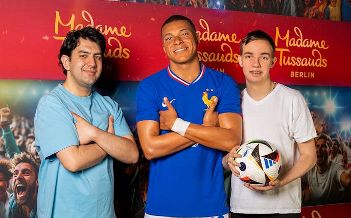 Statue of Kylian Mbappe with visitors at Madame Tussauds, Berlin.
