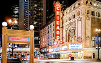 Chicago Theatre marquee lit up at night with nearby subway entrance.