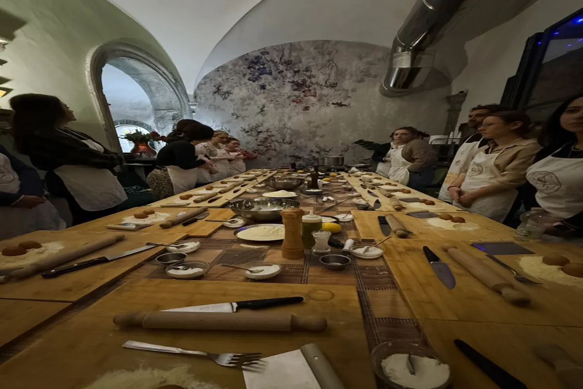 Participants in a pasta and dessert making class in Florence, gathered around a table with ingredients and utensils.