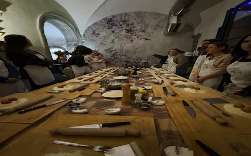 Participants in a pasta and dessert making class in Florence, gathered around a table with ingredients and utensils.
