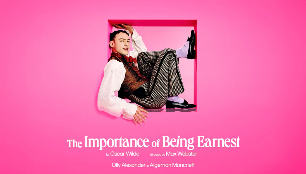 Actor in costume for "The Importance of Being Earnest" against a pink background.