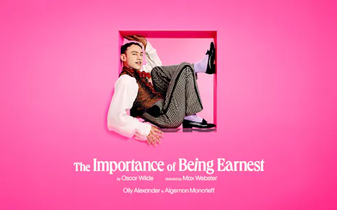 Actor in costume for "The Importance of Being Earnest" against a pink background.
