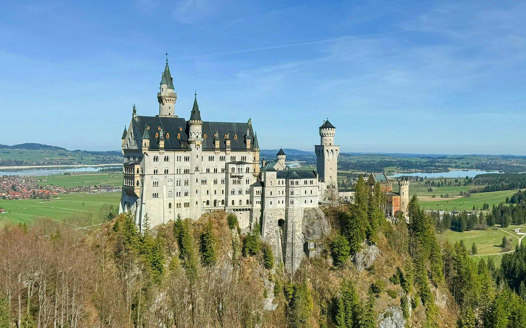 Aerial view of Neuschwanstein Castle surrounded by lush landscape in Bavaria, Germany.
