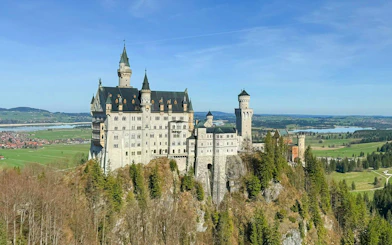 Aerial view of Neuschwanstein Castle surrounded by lush landscape in Bavaria, Germany.