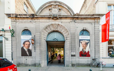 Groeningemuseum entrance with historical portraits in Bruges, Belgium.