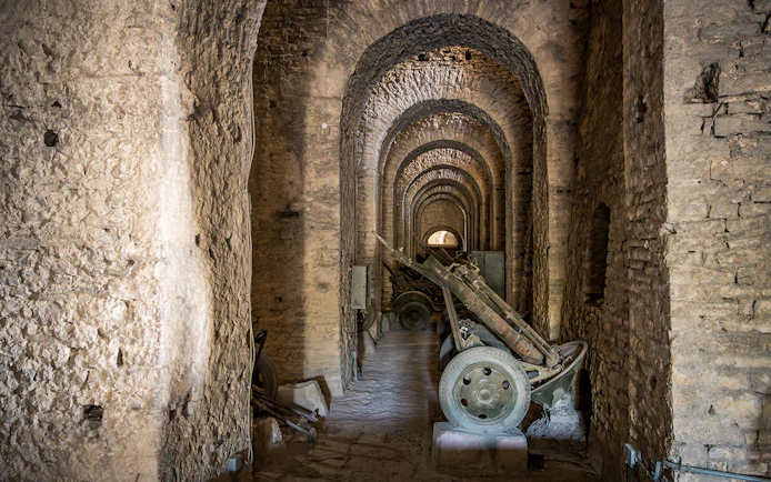 Canons inside Gjirokaster Castle, Albania, in a stone-arched corridor.