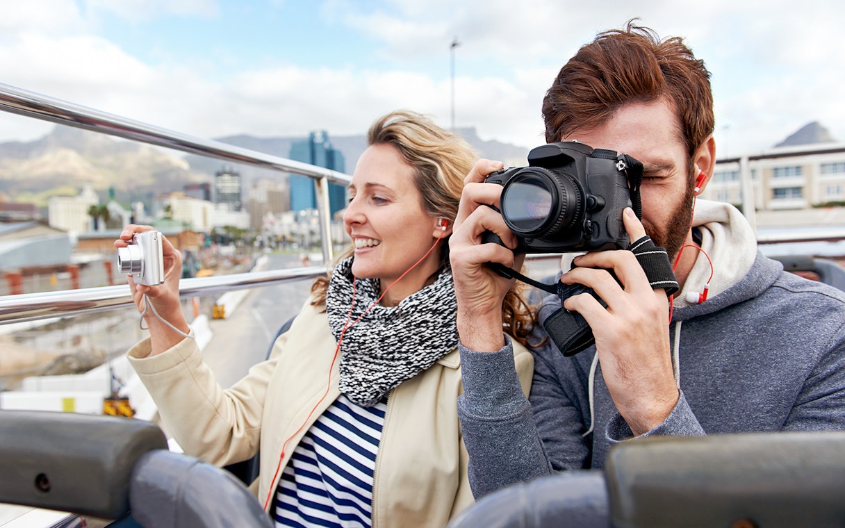 Couple taking photos on a Hop on Hop off bus in London.