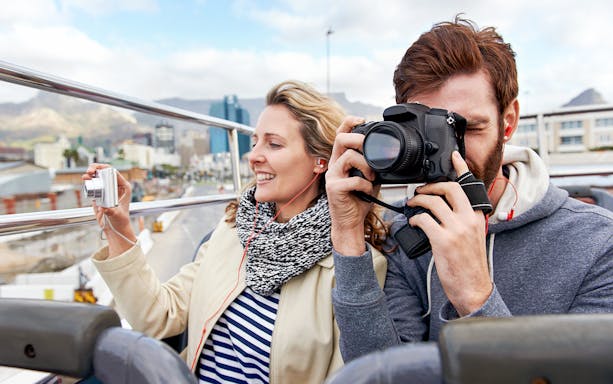 Couple taking photos on a Hop on Hop off bus in London.