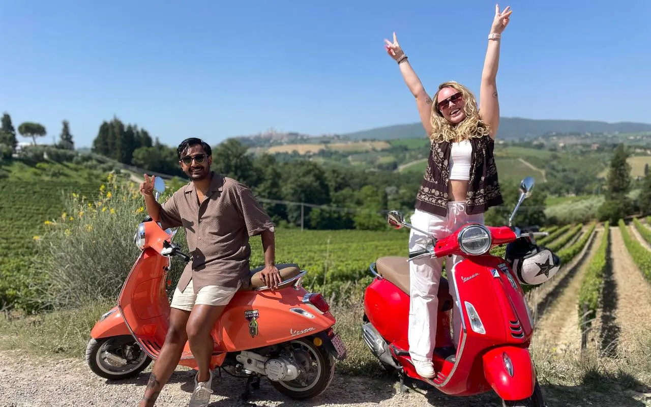 Two people on Vespas in Chianti vineyard, Tuscany, enjoying a private tour.