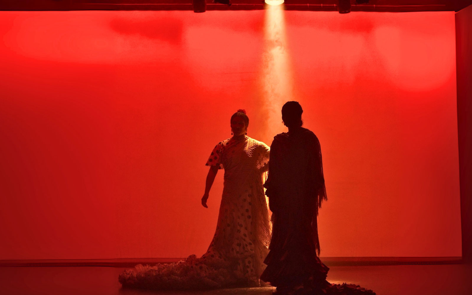 Flamenco dancers performing on stage with red lighting in Barcelona.