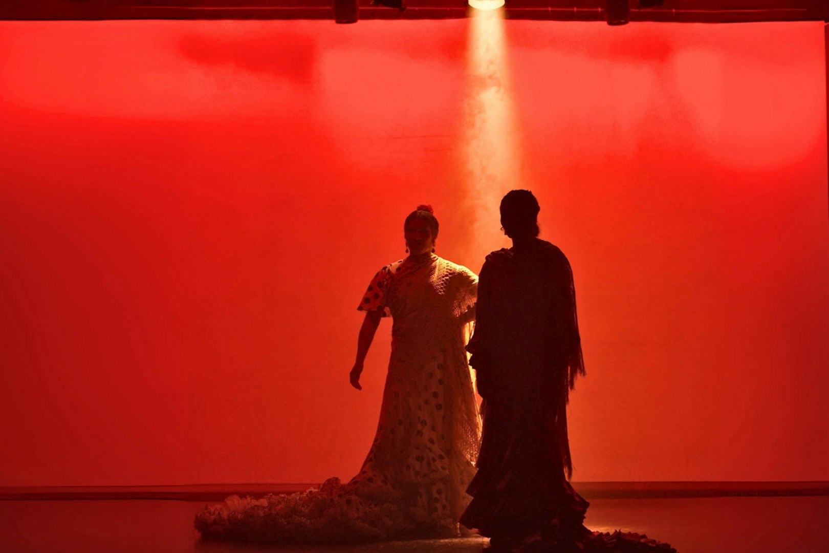 Flamenco dancers performing on stage with red lighting in Barcelona.