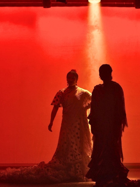 Flamenco dancers performing on stage with red lighting in Barcelona.