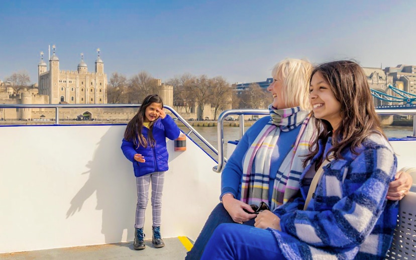 Family enjoying a London sightseeing cruise with Tower of London in the background.